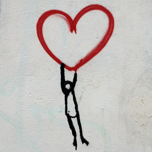 stick figure hanging from heart shape street art spray paint